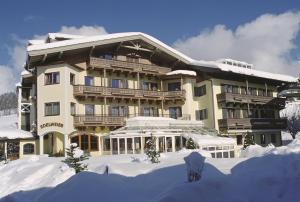 een groot gebouw met sneeuw ervoor bij Hotel Edelweiss in Maria Alm am Steinernen Meer