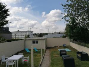 un patio trasero con una mesa y sillas y una valla en Appartement 3 chambres - Parking - Wifi - Buanderie - Jardin, en Brest