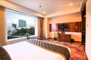 バンガロールにあるKINGSTON HOTELのベッドと大きな窓が備わるホテルルームです。