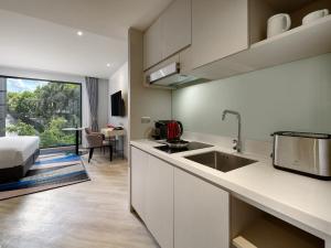 a kitchen with a sink and a bed in a room at Oakwood Studios Sukhumvit Bangkok in Bangkok