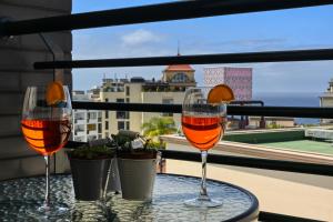 twee glazen wijn zittend op een tafel op een balkon bij Forum Escape, a Home in Madeira in Funchal +27 foto's