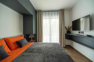 a bedroom with an orange bed and a flat screen tv at Dolomiti Nice1 in Belluno