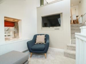 a living room with a blue chair and a tv at The Hayloft in Matlock