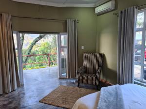 a bedroom with a bed and a chair and a window at Metsing at Harties in Hartbeespoort