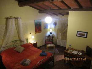 1 dormitorio con cama roja, mesa y silla en Villa Arianna B&B, en Lari