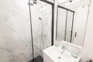 La salle de bains blanche est pourvue d'une douche et d'un lavabo. dans l'établissement Appartement Cosy et Lumineux - Tout équipé - Hypercentre Lorient par Groom, à Lorient