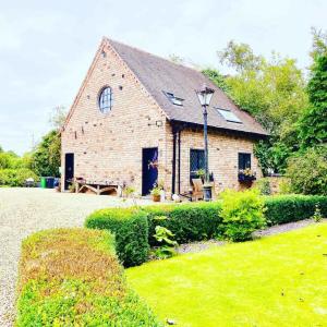 una casa de ladrillo con un banco delante de ella en Private Loft Country Hideaway, en Shifnal