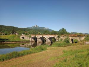 eine Brücke über einen Fluss neben einem Feld in der Unterkunft Apartman 1 RIBIČ in Ogulin