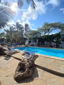 a resort pool with lounge chairs and a rock at Maasai Villas in Mombasa