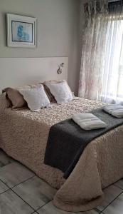 una camera da letto con un grande letto con cuscini e una finestra di Villa Dubaai a Mossel Bay