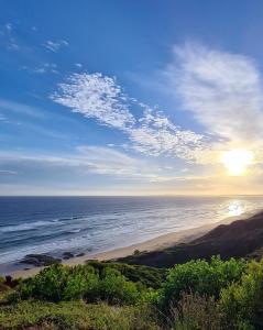 una vista su una spiaggia con il sole che sorge sull'oceano di Villa Dubaai a Mossel Bay