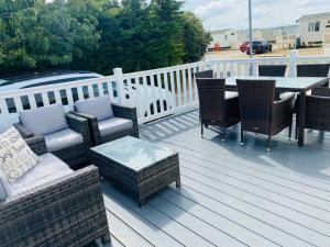 a deck with wicker chairs and a table and a table and chairs at Shell Beach Holiday Home Mersea Coopers Beach in East Mersea +5 photos