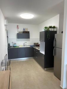 a kitchen with black cabinets and a refrigerator at Nahal Beer sheva נחל באר שבע in Beer Sheva