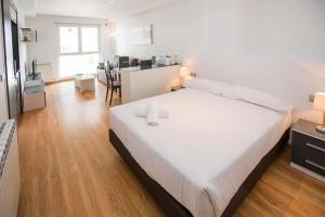 Un dormitorio con una gran cama blanca y una cocina. en The Lodge at Ribasol, en Arinsal