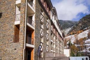 un edificio de ladrillo con montañas en el fondo en The Lodge at Ribasol, en Arinsal