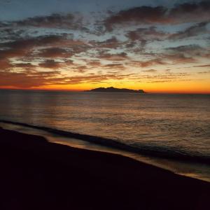 a sunset on the beach with a mountain in the distance at Opalia Suites in Perissa