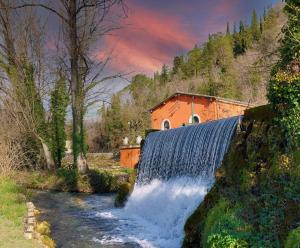 wodospad przed czerwonym budynkiem obok rzeki w obiekcie Casa Rosamari - su Lago di Posta Fibreno, Appartamento con camino w mieście Posta Fibreno