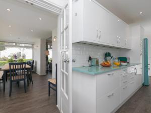 uma cozinha com armários brancos e uma sala de jantar em The Pines em St. Ives