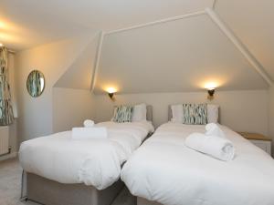 2 camas en una habitación con sábanas blancas y toallas en The Pines en St Ives