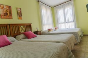 eine Gruppe von 3 Betten in einem Zimmer mit Fenstern in der Unterkunft Casa Rural La Pinta- SendaViva y Bardenas in Villafranca