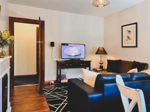 een woonkamer met een blauwe bank en een tv bij Rose Court Apartments "Aristone" in New Town