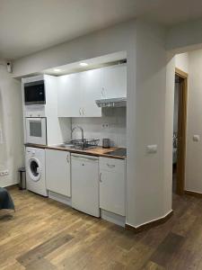 cocina con armarios blancos, lavadora y secadora en Portalegre, en Madrid