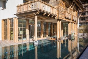 a house with a swimming pool with a wooden deck at Raffl's Tyrol Hotel in Sankt Anton am Arlberg
