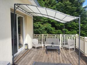 a pergola on a deck with chairs and a table at La Maison des Joel's in Schorbach