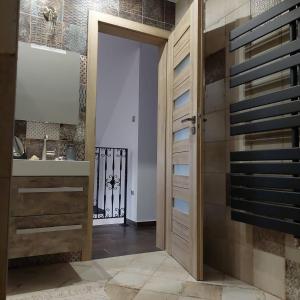 baño con puerta de madera y lavamanos en Dr Becsey Luxury Apartman en Békéscsaba