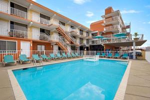 a swimming pool at a hotel with chairs and a building at Days Inn & Suites by Wyndham Wildwood in Wildwood