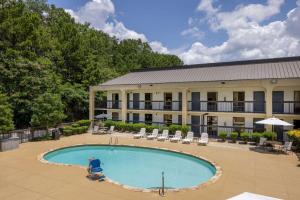 a hotel with a pool and chairs and a building at Baymont by Wyndham Columbus GA in Columbus