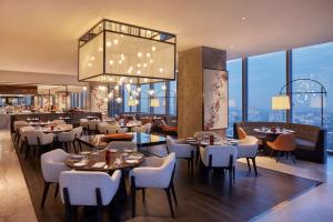 a restaurant with tables and chairs and a chandelier at Park Hyatt Jakarta in Jakarta