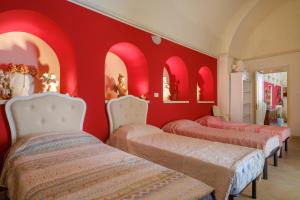 Zimmer mit roten Wänden, 3 Betten und Spiegeln in der Unterkunft Appartamento 2 - Palazzo Costantini in San Donato di Lecce