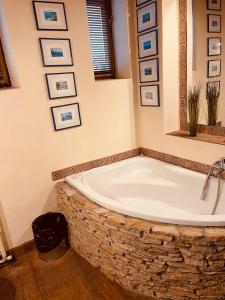 een bad in een badkamer met foto's aan de muur bij VillaPark Garden House in Szerencs