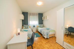 札格雷布的住宿－Sunny day -Arena Zagreb , 2 bathrooms, 102m²,，酒店客房带两张床、书桌以及一间客房。