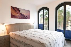 a bedroom with a large bed and two windows at Baabe Villa Andrea Ferienwohnung P in Baabe