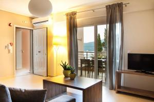salon ze stołem i telewizorem oraz balkonem w obiekcie Eucalyptus Apartments Apartment Meli w mieście Karavomylos