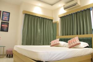 Schlafzimmer mit einem großen Bett und grünen Vorhängen in der Unterkunft LA CRESTA INN in Kalkutta