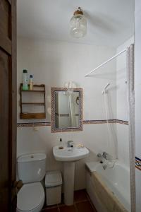 een badkamer met een toilet, een wastafel en een bad bij Don Claudio in Grazalema