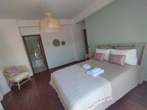 a bedroom with a large bed and a chair at Casa Flor de Mel in Sertã