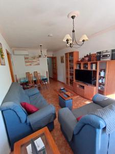 una sala de estar con 2 sofás azules y una mesa. en Apartamento Merlin, en Roquetas de Mar
