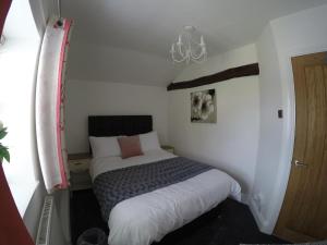 Habitación pequeña con cama y lámpara de araña. en Daisy Cottage en Wakefield