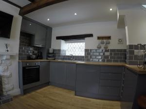 a large kitchen with gray cabinets and a sink at Daisy Cottage in Wakefield +3 photos