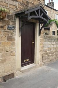 a brown door on a stone building with a cross at Daisy Cottage in Wakefield