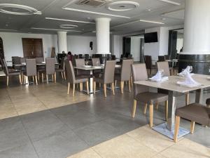 Hotel Franco Yaounde في ياوندي: غرفة طعام بها طاولات وكراسي وتلفزيون