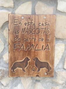 a wooden sign with two dogs on a stone wall at Posada Pet Friendly El Molino de Cantabria in Entrambasaguas
