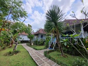 een huis met een palmboom naast een loopbrug bij The Akah Cottage - CHSE Certified in Nusa Lembongan