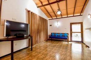 ein Wohnzimmer mit einem blauen Sofa und einem TV in der Unterkunft Dolagawa in Deniyaya