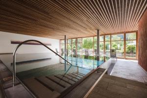 a house with a swimming pool with a wooden ceiling at Hotel Monte Sella in San Vigilio Di Marebbe
