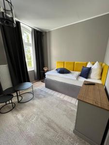 ein Schlafzimmer mit einem Bett mit einem gelben Sofa und einem Tisch in der Unterkunft Gutshauszimmer Neu Gaarz in Neu Gaarz